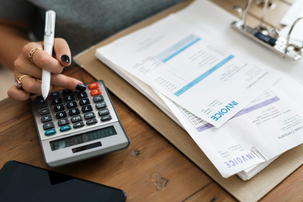 Woman with pen and calculator gooing over the bills at her desk.