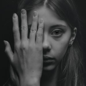 Young girl hiding the right hand side of her face with her hand